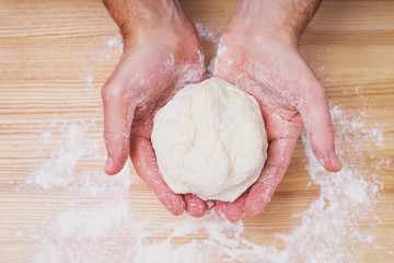 Close-up shot of man's hands holding homemade dough