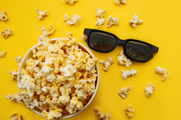 Bowl with popcorn and 3d glasses on a yellow background. Top view.