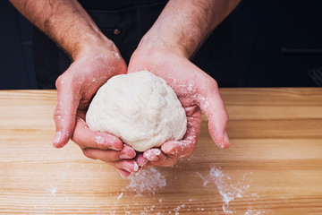 Close-up shot of man's hands holding homemade dough