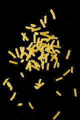 Italian flying raw pasta isolated on black background. macaroni fusilli falling.