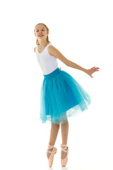 Naklejka premium Cute little girl in a tutu and pointe shoes dancing in the studio.