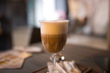 Cappuccino and a slice of cake on a table in a cafe.