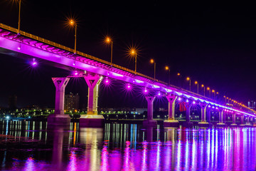 Fototapeta na wymiar Colorfully lit bridge and the night city