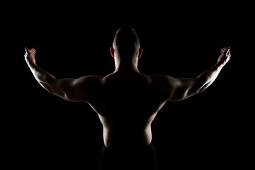 Fototapeta na wymiar Healthy muscular young man with his arms stretched out isolated on black background