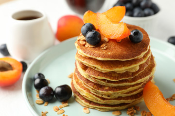 Composition with pancakes and fruits on white table. Sweet breakfast