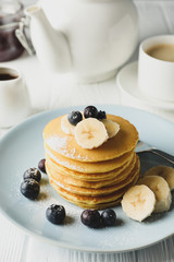 Composition with pancakes, banana and blueberry on wooden background. Sweet breakfast