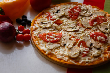 Hot italian pizza on a table with vegetables