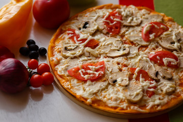 Hot italian pizza on a table with vegetables