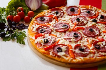 Hot italian pizza on a table with vegetables
