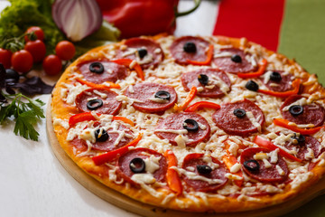 Hot italian pizza on a table with vegetables