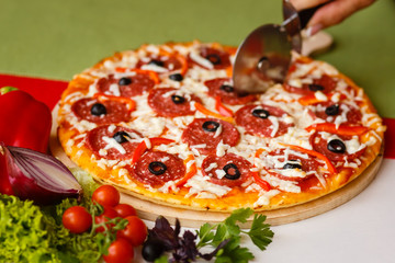 Cutting a pizza to a slices by cutter. Close-up photo