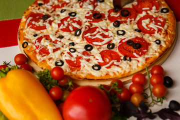 Hot italian pizza on a table with vegetables