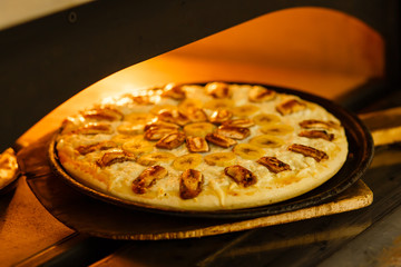 Baking a pizza in oven. Hot pizza in a dish on a shovel in a furnace.