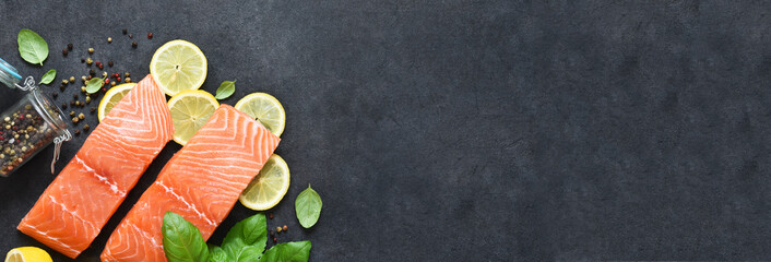 Slice of salmon filet with lemon, basil and spices on a black background.Flatly food