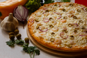 Hot italian pizza on a table with vegetables