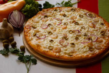 Hot italian pizza on a table with vegetables