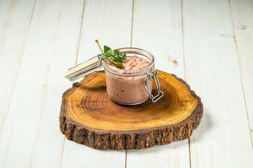 Chicken liver pate in a glass jar wooden board