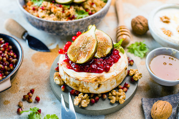 close-up view of tasty healthy dish with fruits, nuts, honey, camembert cheese, couscous and pomegranate seeds on wooden table