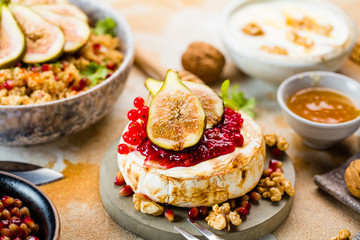 close-up view of tasty healthy dish with fruits, nuts, honey, camembert cheese, couscous and pomegranate seeds on wooden table