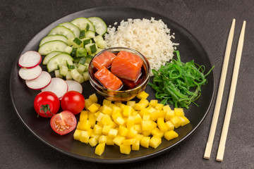 Poke Salad with rice, radish and seaweed in black plate. Asian food. Bamboo chopsticks
