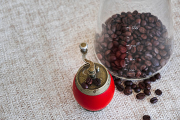 Coffee beans in a measurement glass, with an old grinder on table.