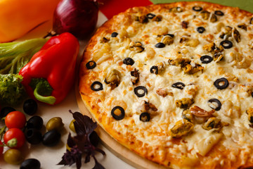 Hot italian pizza on a table with vegetables