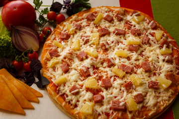 Hot italian pizza on a table with vegetables