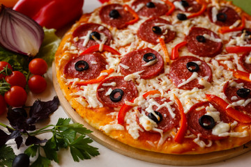 Hot italian pizza on a table with vegetables