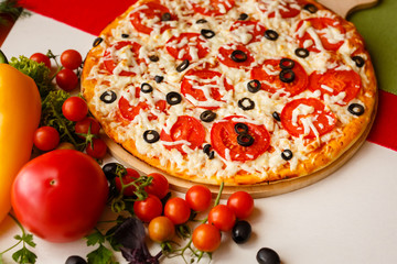 Hot italian pizza on a table with vegetables