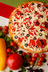 Hot italian pizza on a table with vegetables