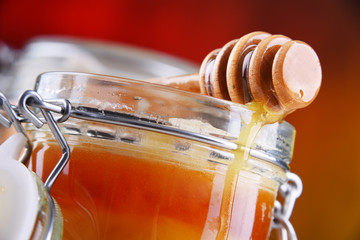 Composition with stick and open jar of honey