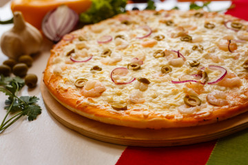 Hot italian pizza on a table with vegetables