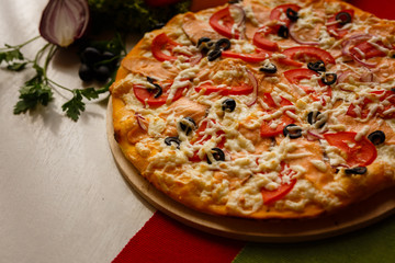 Hot italian pizza on a table with vegetables