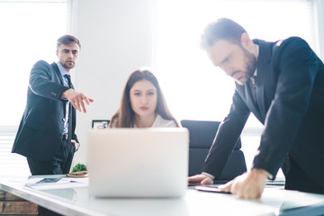 Group of concentrated coworkers browsing laptop