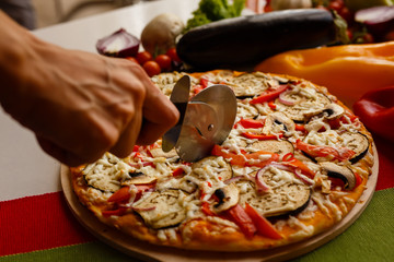 Cutting a pizza to a slices by cutter. Close-up photo