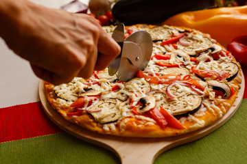 Cutting a pizza to a slices by cutter. Close-up photo