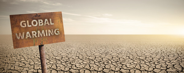 Rusty sign with text "Global warming" on a background of dry cracked desert.  Climate change concept.