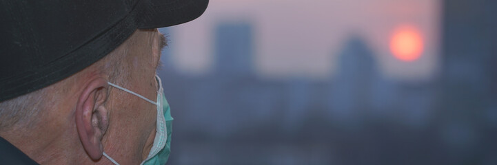 old male person wearing protective face mask and cap looking through window on nigth city street