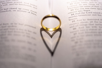 Fototapeta premium A wedding Ring on the bible with shadow of heart shape on the page