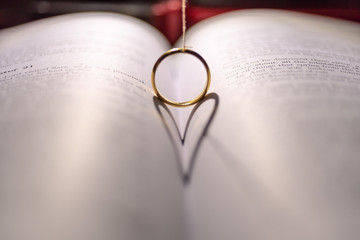 Fototapeta premium A wedding Ring on the bible with shadow of heart shape on the page