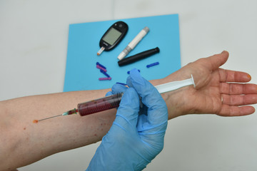 A macro shot of a hand holding a syringe full of blood about to penetrate the arm 