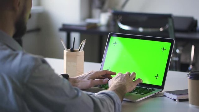 man working on laptop with green screen at office. Spbd chroma key computer for business chroma key purposes. concept display, communication, hands typing. modern interior
