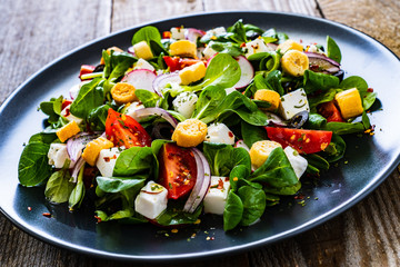 Fresh greek salad - feta cheese, cherry tomatoes, lettuce and onion wooden table
