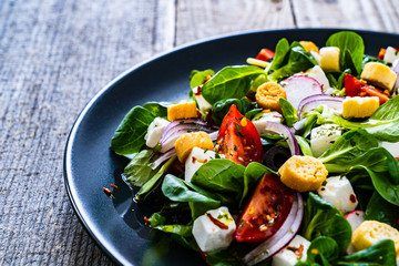 Fresh greek salad - feta cheese, cherry tomatoes, lettuce and onion wooden table
