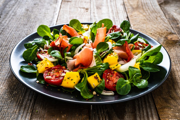 Tasty salad - ham and vegetables on wooden background