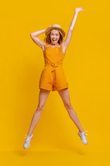 Summer Fun. Joyful Young Girl In Jumpsuit And Hat Jumping In Air