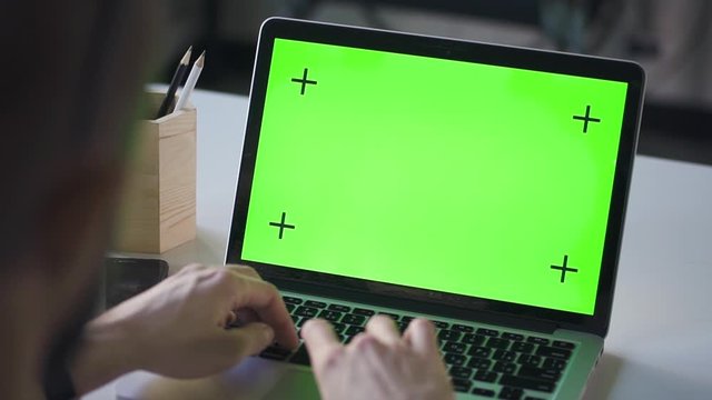 man student working on laptop computer with green screen at office table. Spbd chroma key for keying job study teaching. concept screen, communication, internet. browsing network