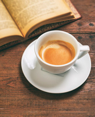 Vintage book and a cup of coffee on wooden background. Break, appointment at a cafe with an espresso and a book