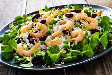 Prawns with rice and vegetables on wooden table
