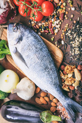 Raw fish on wooden background. Fresh, healthy uncooked whole silver color fish on wood cutting board.